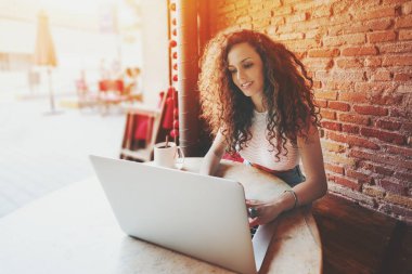 Kafede dizüstü bilgisayar üzerinde çalışan kıvırcık kadın serbest meslek