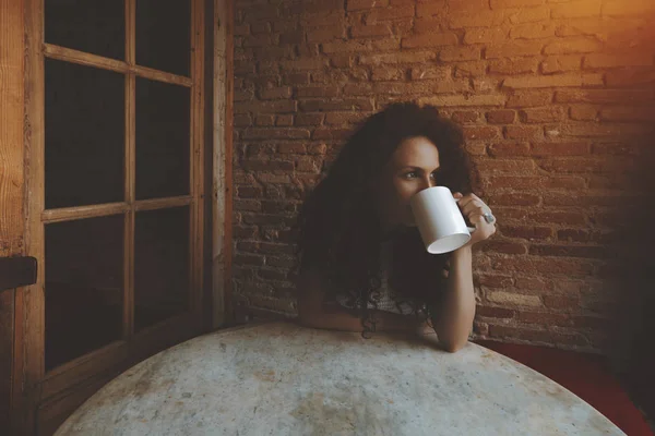 カフェでお茶やコーヒーを飲む巻き毛の少女 — ストック写真