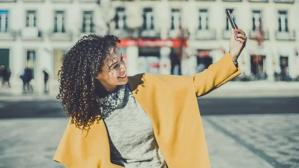 Sonriendo rizado brasileño mujer está haciendo selfie —  Fotos de Stock