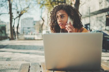 Kıvırcık bayanla telefonda konuşurken laptop