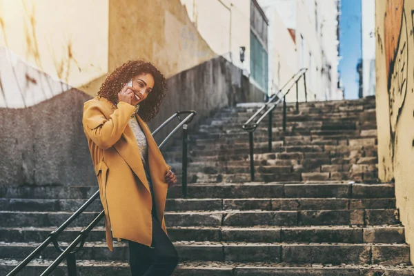 Smiling curly woman talking on smart phone — Stock Photo, Image