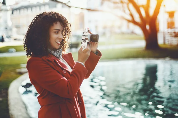 Krullend vrouw in de buurt van de vijver met vintage camera — Stockfoto