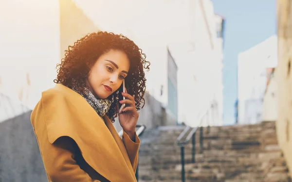 Serious curly lady talking on smart phone — Stock Photo, Image