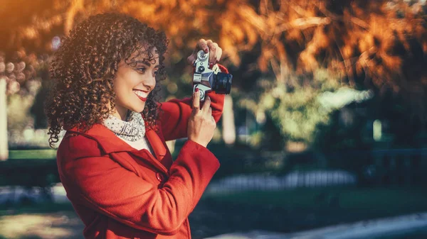 Smiling curly woman with vintage camera — Stock Photo, Image