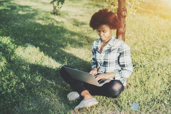 Negro chica rizada con ordenador portátil en el parque — Foto de Stock