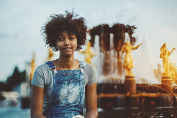 Zwart curly girl zit voor fontein — Stockfoto