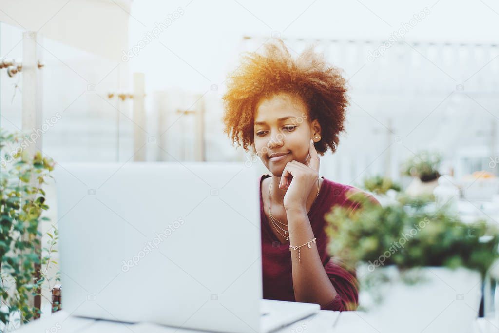 Afro american cute girl with laptop in cafe outdoors