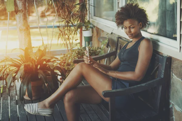 Krullend zwart meisje met telefoon op de Bank — Stockfoto