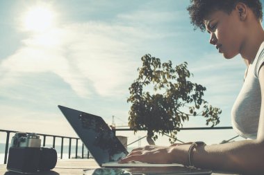 Dizüstü bilgisayarda çalışan dalgın siyah kadın