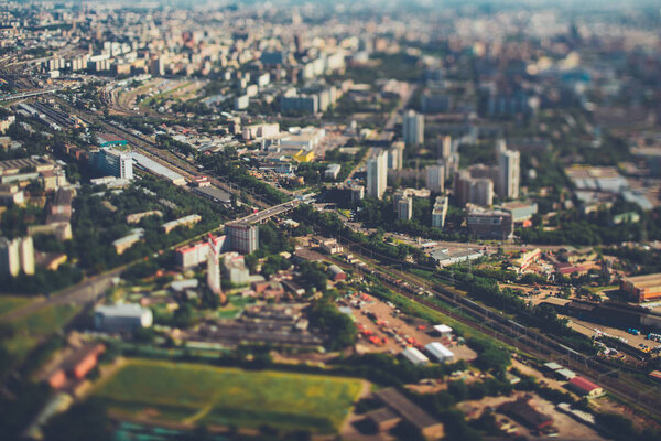 True tilt-shift view from very high above of railway with several tracks, aerial view of railroad station in focus surrounded by defocused residential districts and industrial zone, Moscow, Russia