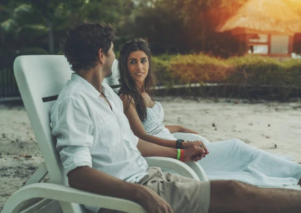 Adult newlyweds sitting on chaise longue on a beach — Stock Photo, Image