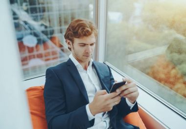 Adam işveren Divan pencere yakınındaki smartphone ile