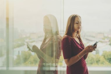İşkadını pencere yakınındaki cep telefonu ile Kırmızı elbiseli