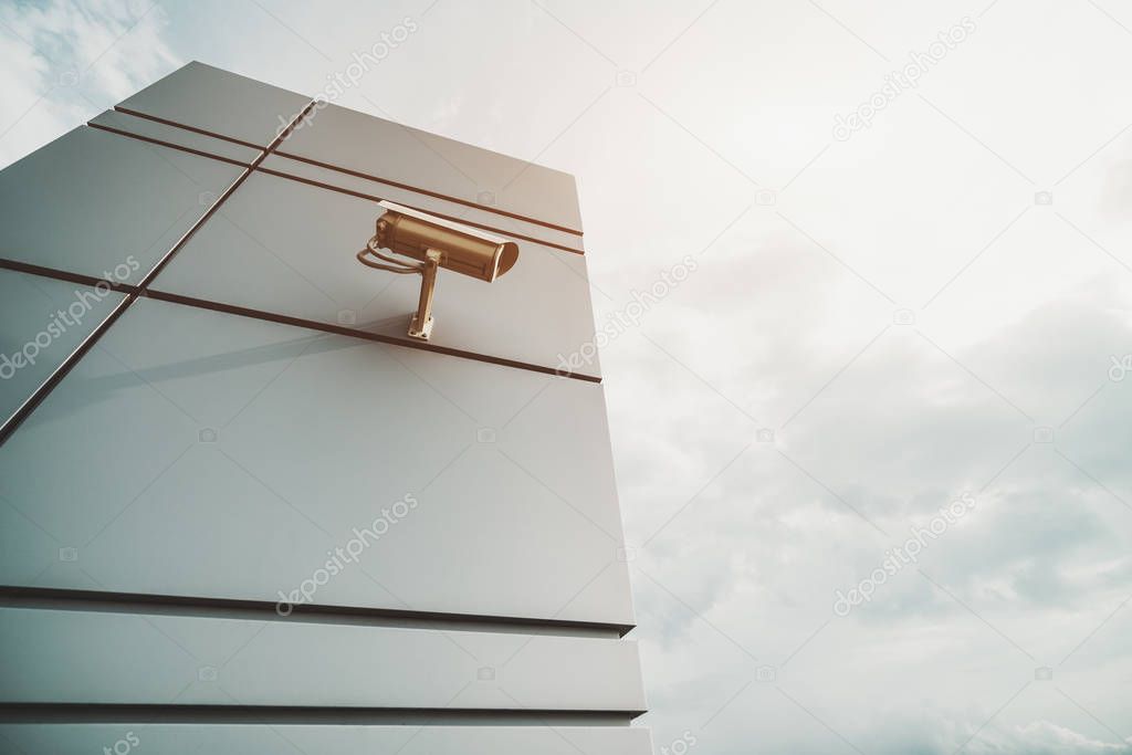 Wide-angle shooting  from bottom of surveillance camera fixed to modern metal wall with stripes on which it casts long shadow; bright sunny day with copy space zone for text your logo or advertising