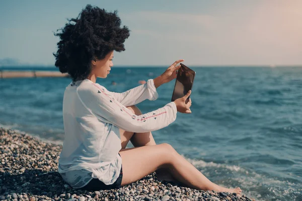 Ebano ragazza prendendo selfie mentre seduto su spiaggia — Foto Stock