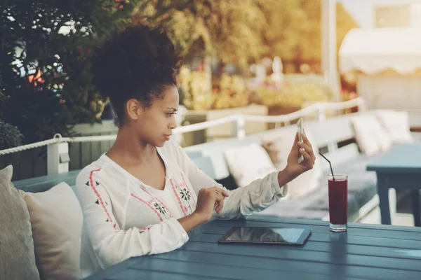 Menina birracial no bar de rua com smartphone e pad digital — Fotografia de Stock
