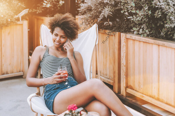 Бразильская девушка говорит по телефону в уличном баре
