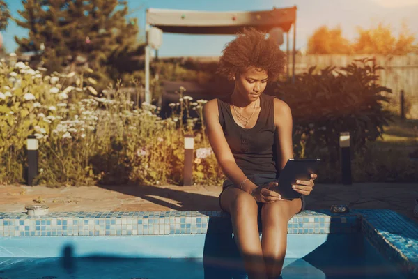 Chica brasileña rizada en la piscina con almohadilla digital — Foto de Stock