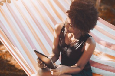 Dijital pad ile bahçesinde hamak biracial Bayan