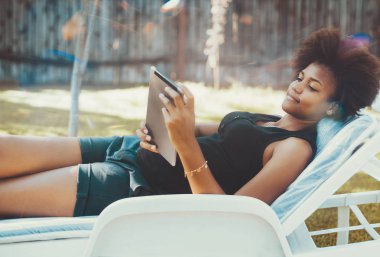 Dijital tablet ile şezlong üzerinde Afro kız