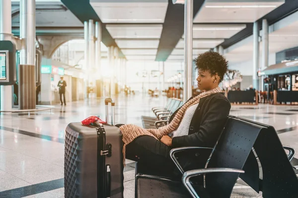 Чернокожая девушка ждет своего рейса в аэропорту — стоковое фото