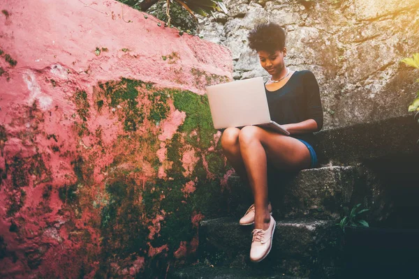 Exquisite young black woman with netbook on stony step — Stock Photo, Image