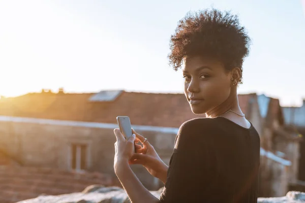 Mujer Biracial con teléfono celular en el techo — Foto de Stock