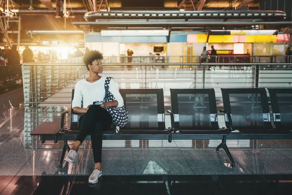 Черная девушка ждет свой самолет в терминале аэропорта — стоковое фото