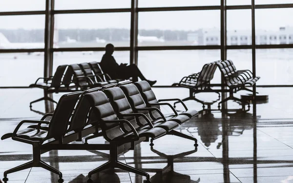 Airport departure hall with silhouette of sitting man