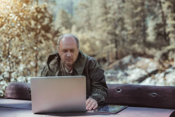 Mature male hunter with tablet pc and laptop — Stock Photo, Image