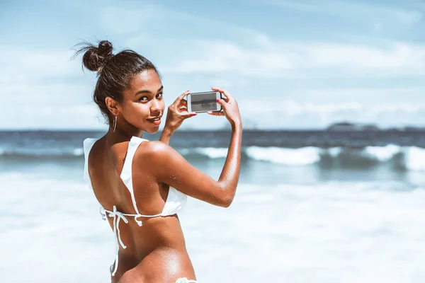 Menina preta com smartphone na praia — Fotografia de Stock