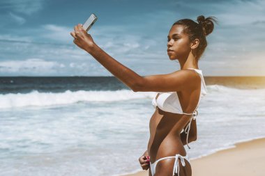 Black girl on the beach taking selfie clipart