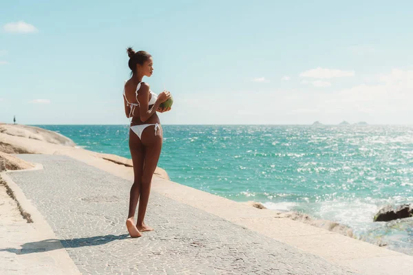 Чорна дівчина з кокосом на березі моря — стокове фото