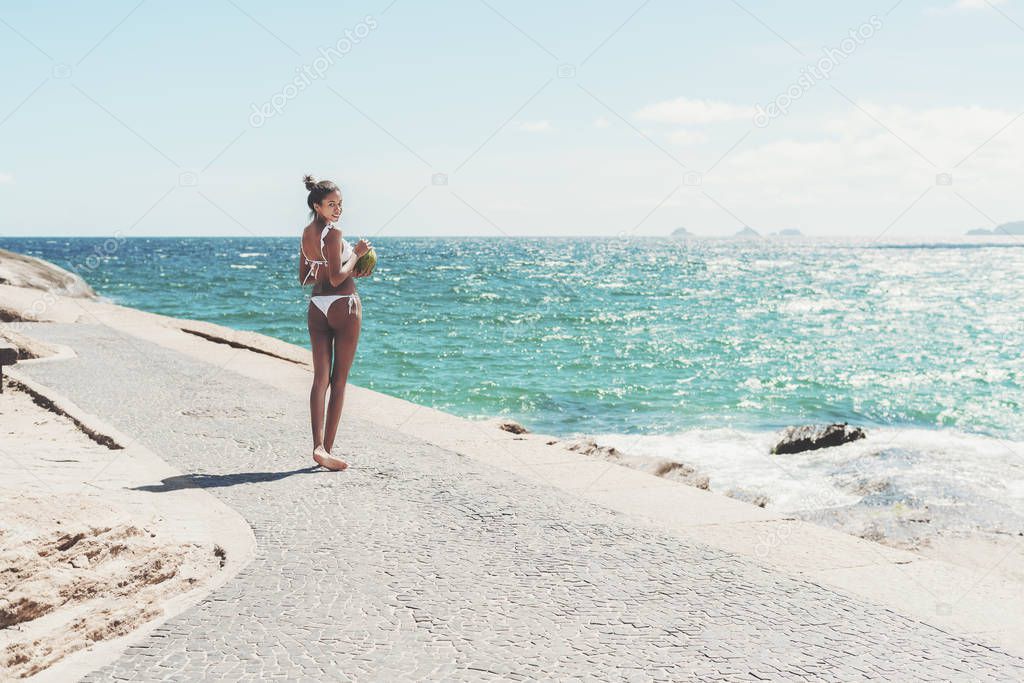 Brazilian young girl on the ocean embankment with coco