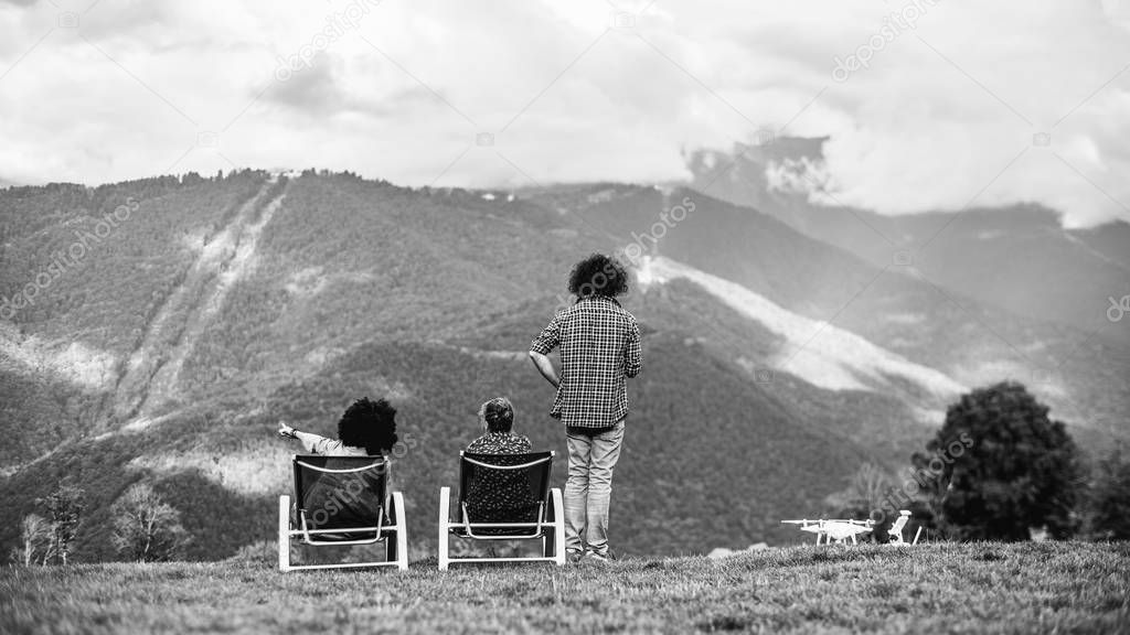 Grayscale mountain scenery with silhouettes of trhee people and 