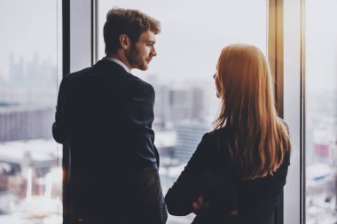 İşadamı ve ofis pencere yakınındaki konuşan iş kadını