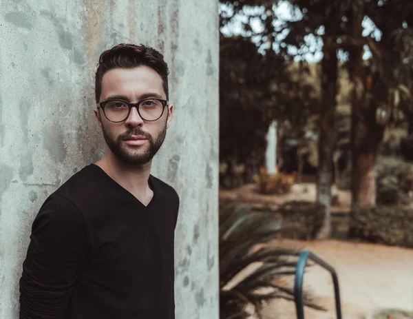 Hombre barbudo con anteojos cerca de la pared —  Fotos de Stock