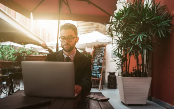 Jonge knappe man werkgever in restaurant buiten met laptop — Stockfoto