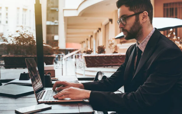 Man employer in glasses with laptop in street restaurant