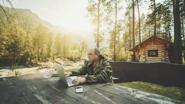 Man entreprenör nära sitt sommarhus med laptop — Stockfoto