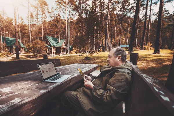 Muž s digtial tablet a notebook v lese — Stock fotografie