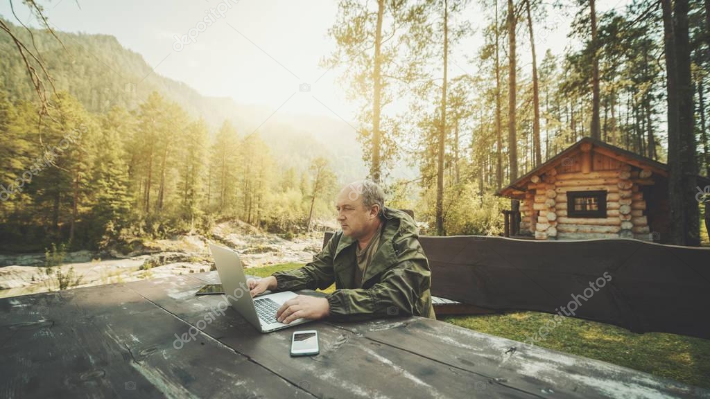 Man entrepreneur near his summer house with the laptop