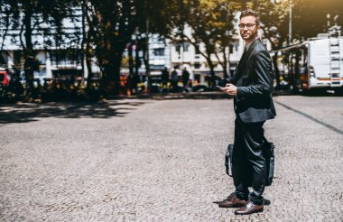 Adam girişimci ile smartphone bir güneşli sokak