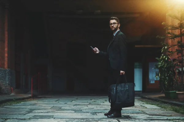 Empresário com saco e smartphone ao ar livre — Fotografia de Stock
