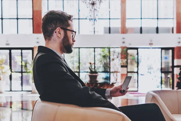 Affärsman med smartphone i fåtölj inomhus — Stockfoto