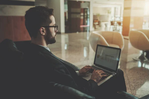 Affärsman med skägget och netbook i office lobby — Stockfoto