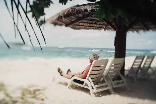 Caucasian senior tourist on the resort daybed next to sea — Stock Photo, Image