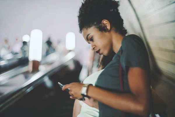 Black girl with cell phone on the elevator inside metro — Stock Photo, Image