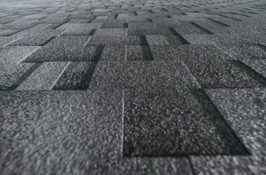 Yumuşak çatı üst kısmında güneş tarafından yaktı bir yazlık ev gri grenli doku döşeli; bir bina kapsayan yumuşak çatı kiremit gri, orta mesafe üzerinde odak