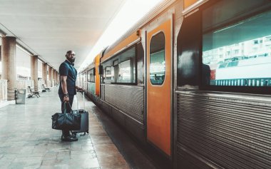 Afro işadamı trene giriyor.
